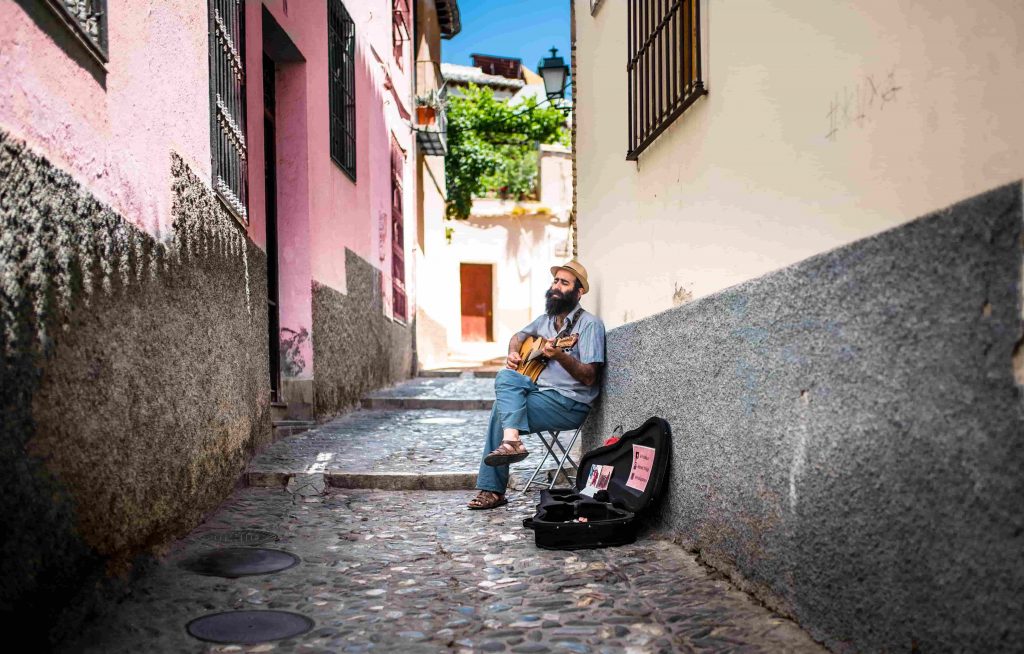 A person playing a guitar and signing outside.