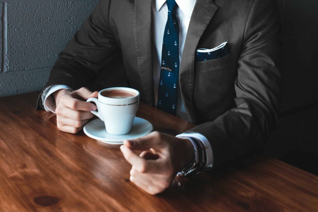 Image of a person in a suit with a coffee.